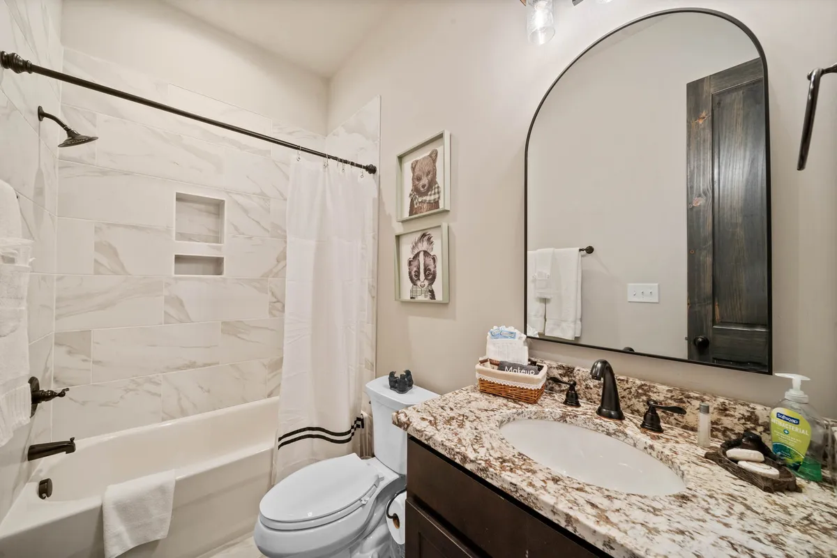 A bathroom scene with a granite countertop, an oval mirror, and tasteful framed art. The space is modern yet warm, offering a sense of calm and self-care.