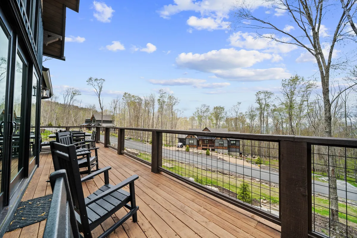 The photo showcases a wooden deck with classic rocking chairs facing a landscape view. The scene captures tranquility and invites guests to relax while enjoying the outdoors, making it perfect for taking in sunrises, sunsets, or autumn foliage.