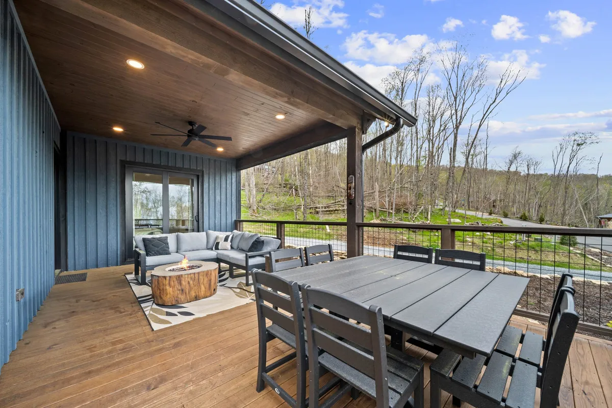 A cozy outdoor seating area is arranged around a fire pit, with a dining table nearby and panoramic views stretching over the surrounding landscape. The scene is bathed in warm evening light, inviting guests to relax, dine, and connect while enjoying the outdoors.