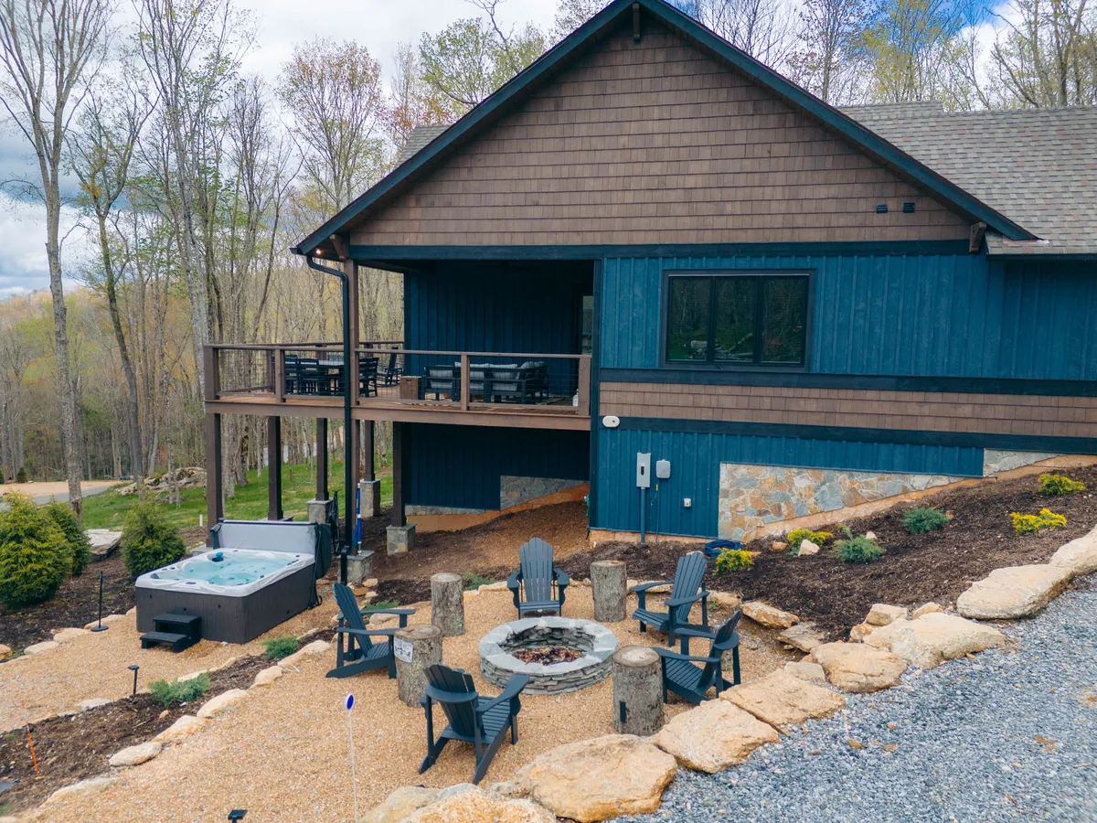 A cozy outdoor space featuring a hot tub, fire pit, ample seating, and a wooden deck, all positioned to maximize enjoyment of sunsets and starlit nights. The arrangement invites both intimate relaxation and social gatherings.