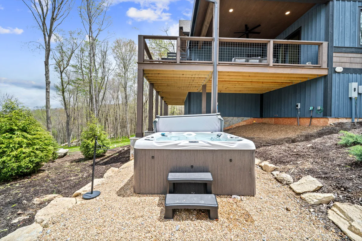 A tranquil scene featuring a hot tub on a wooden deck with a tree-lined backdrop. The view from the tub showcases the surrounding wilderness and the potential for stargazing or wildlife observation after a day of adventure.